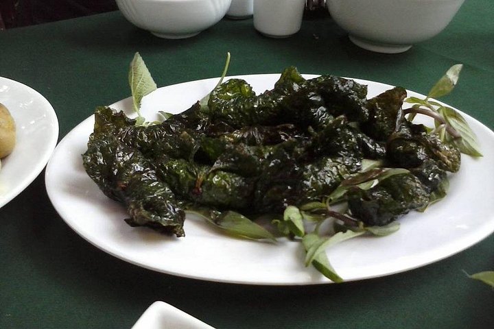 Leaf-wrapped dishes served with fresh herbs on a white platter in Le Mat Village.
